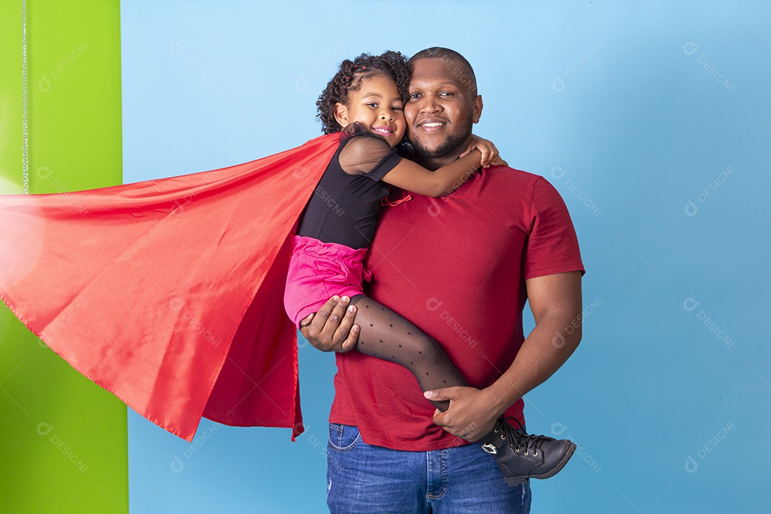 Pai e filha juntos com capa de super herói em fundo azul