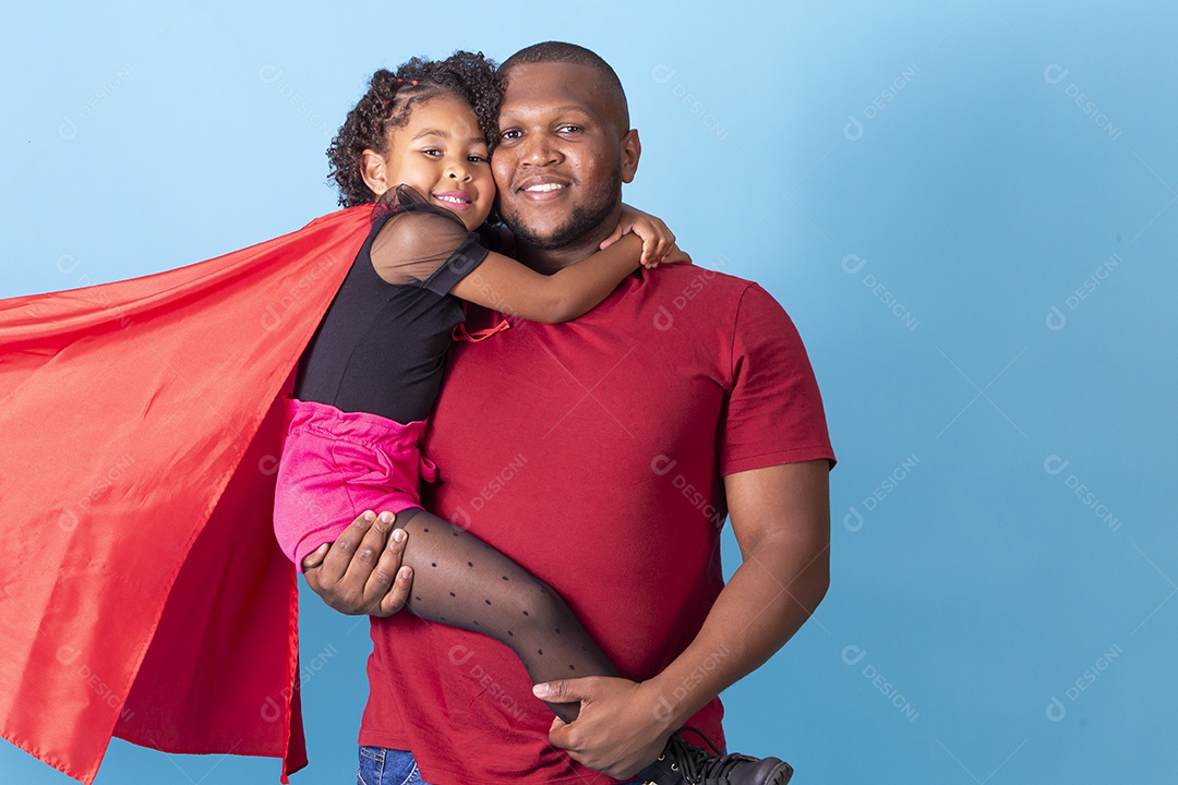 Pai e filha juntos com capa de super herói em fundo azul