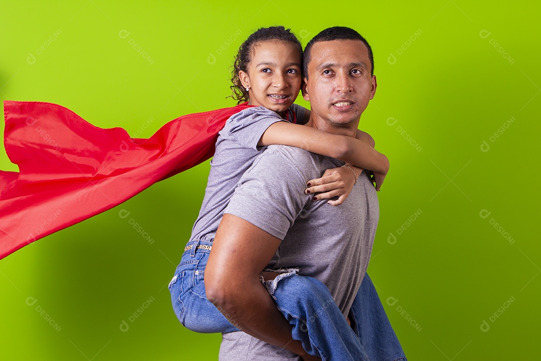 Pai e filha juntos com capa de super herói em fundo verde