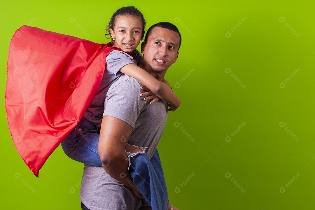 Pai e filha juntos com capa de super herói em fundo verde