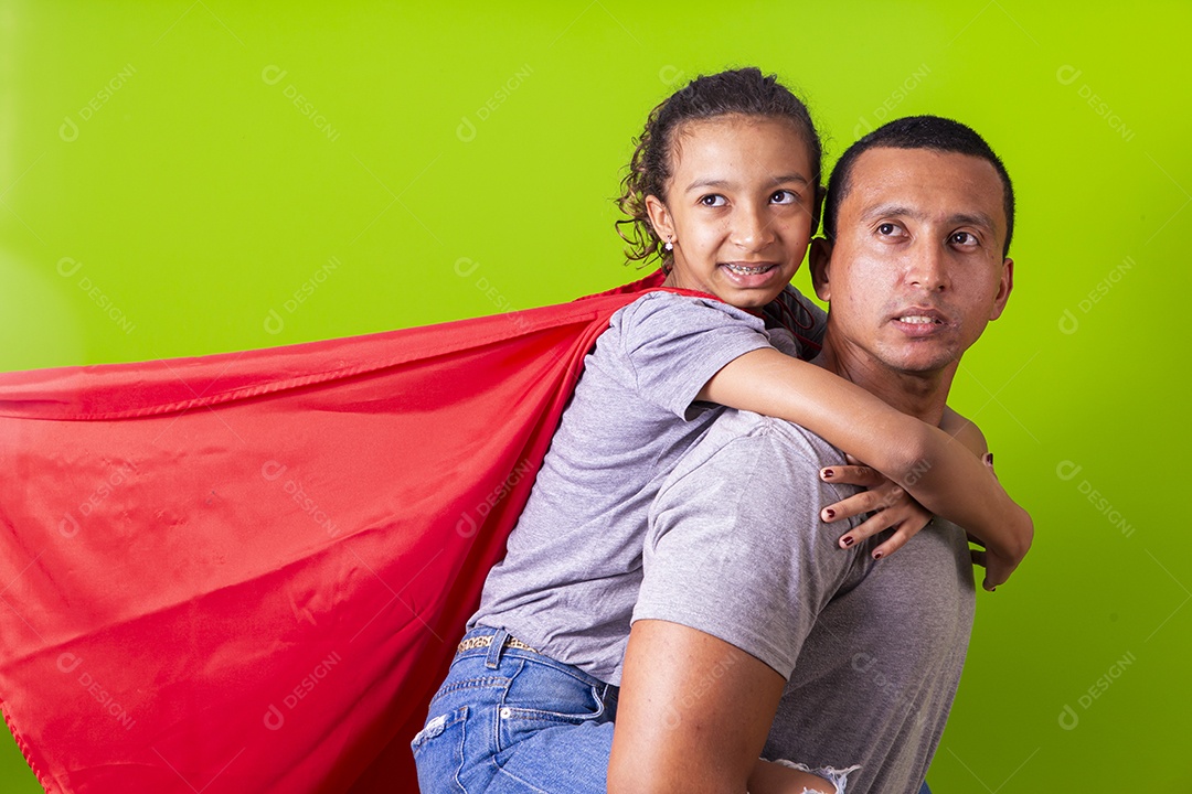 Pai e filha juntos com capa de super herói em fundo verde