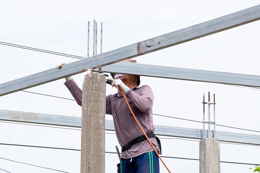 Homens trabalhadores da construção civil soldando vigas de aço do telhado, homem trabalha com uma máquina de solda e metal