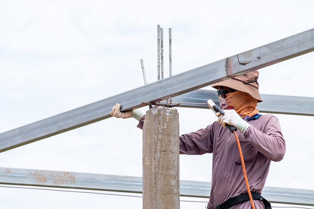 Homens trabalhadores da construção civil soldando vigas de aço do telhado, homem trabalha com uma máquina de solda e metal
