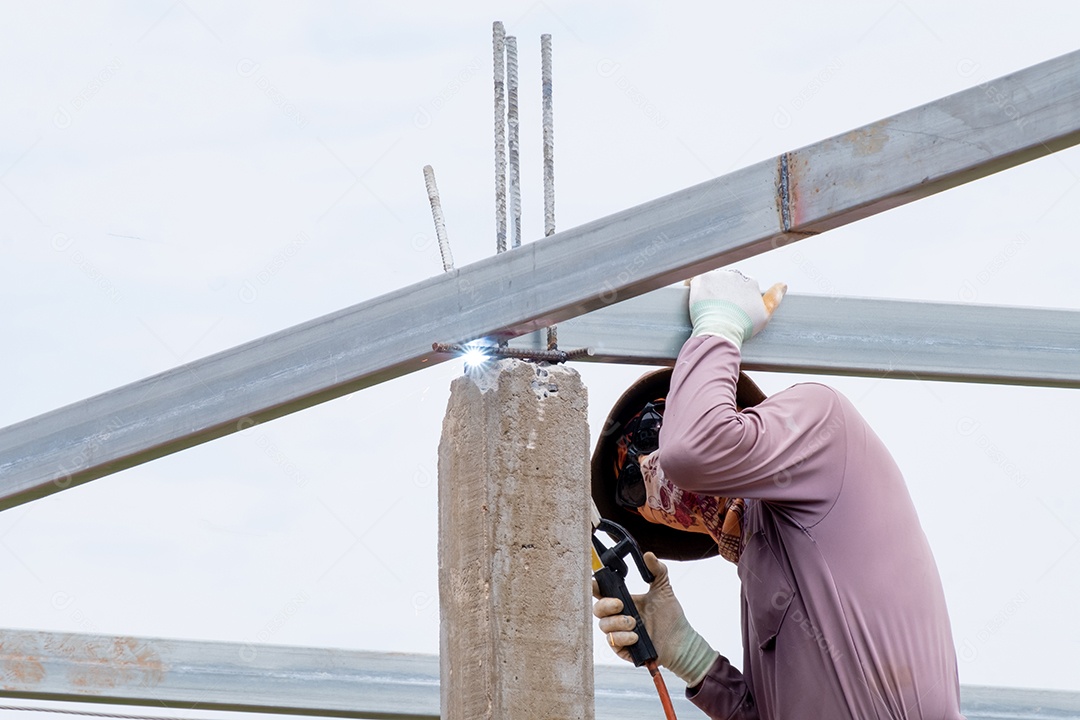 Homens trabalhadores da construção civil soldando vigas de aço do telhado, homem trabalha com uma máquina de solda e metal