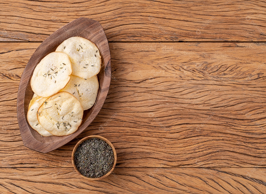 Lascas de queijo provolone defumado em uma tigela com orégano sobre mesa de madeira com espaço de cópia.