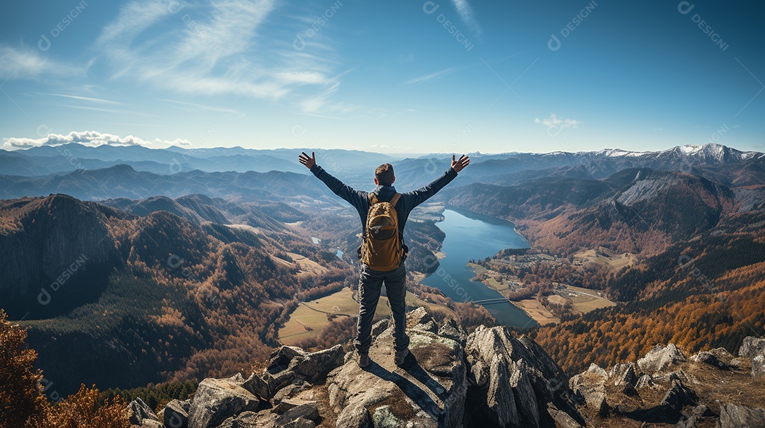 Um homem mantém os braços abertos de sucesso depois de caminhar até o topo de uma montanha.