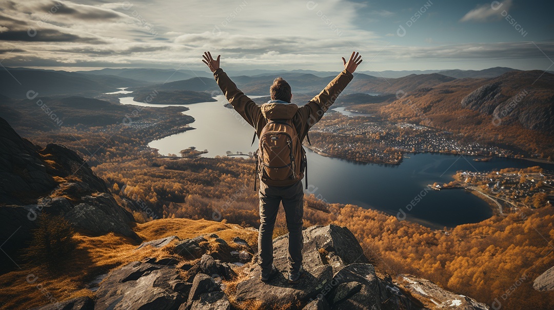 Um homem mantém os braços abertos de sucesso depois de caminhar até o topo de uma montanha.