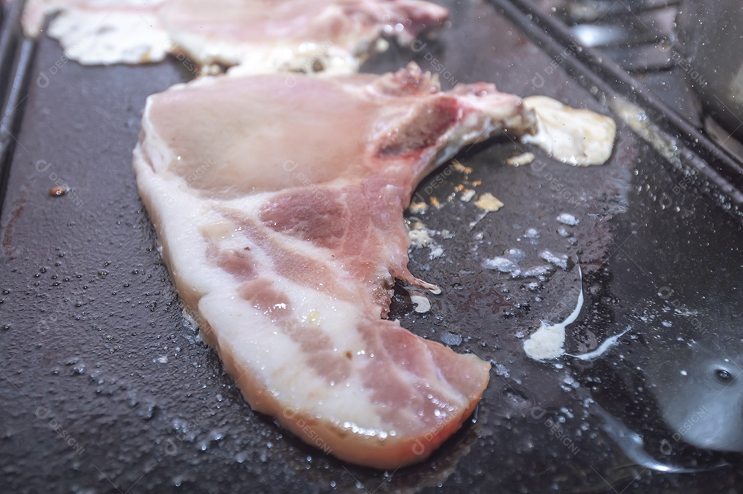 Bife suíno em um churrasco caseiro que fica em cima do fogão