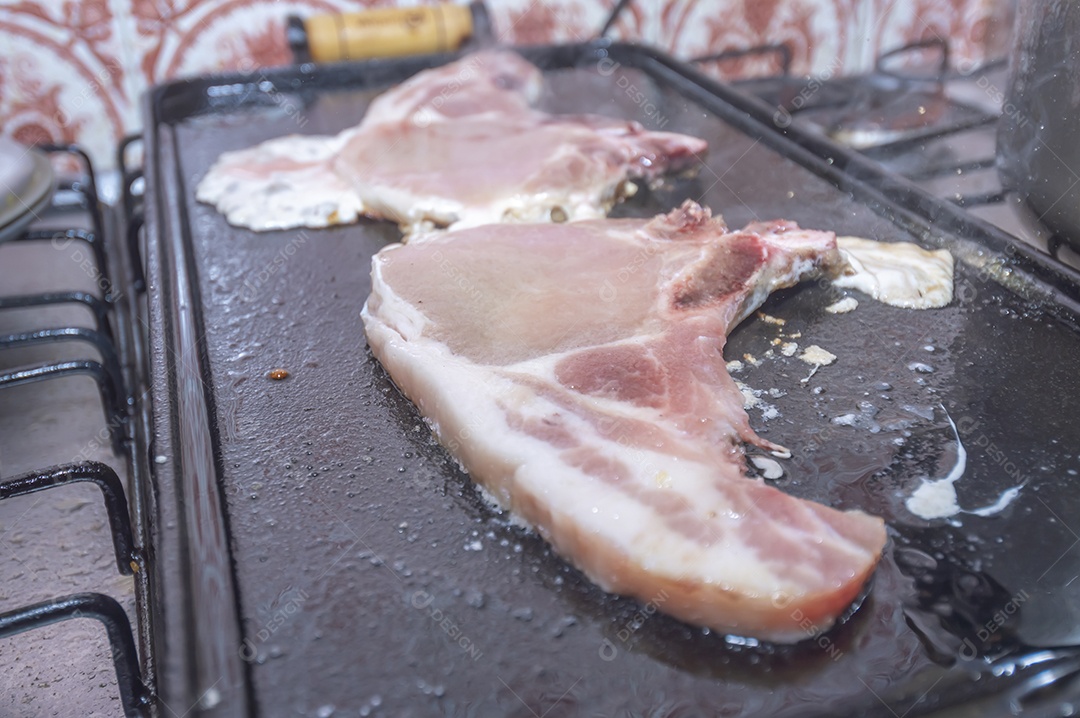 Bife suíno em um churrasco caseiro que fica em cima do fogão