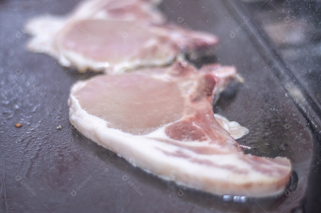 Bife suíno em um churrasco caseiro que fica em cima do fogão
