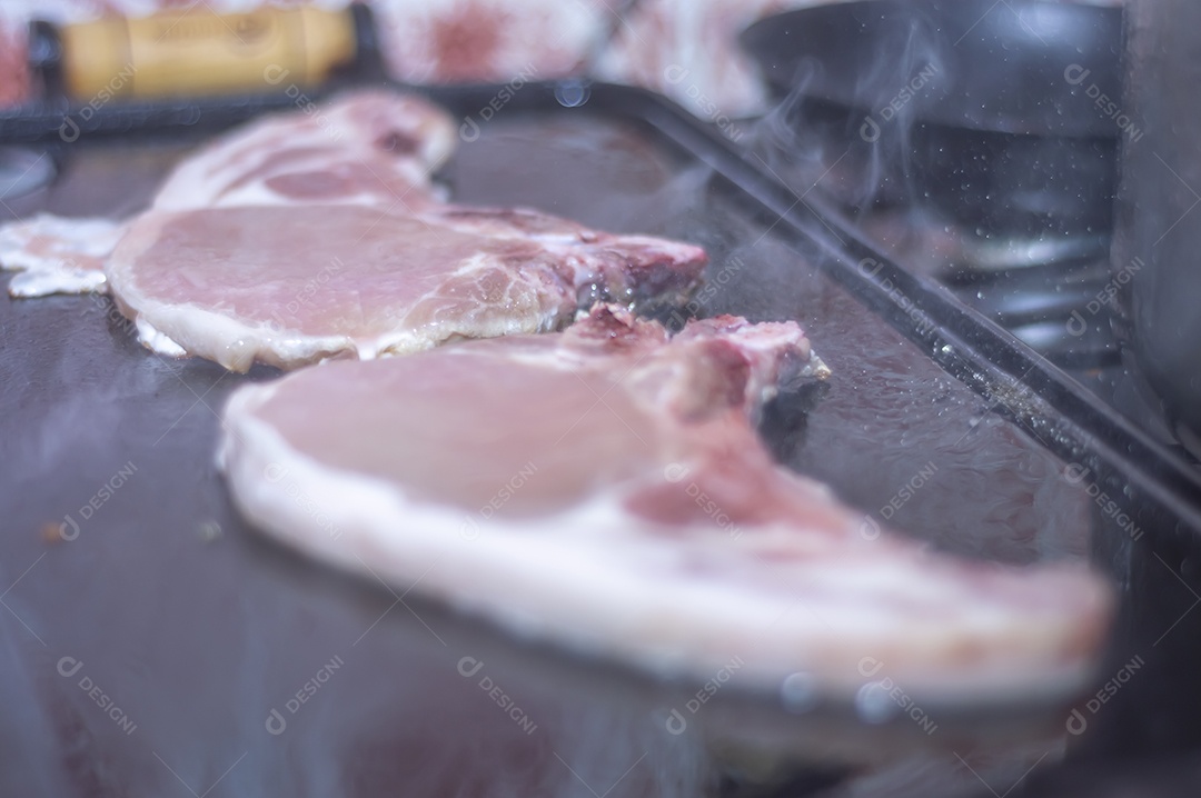 Bife suíno em um churrasco caseiro que fica em cima do fogão, conceito de fazer comida em casa.