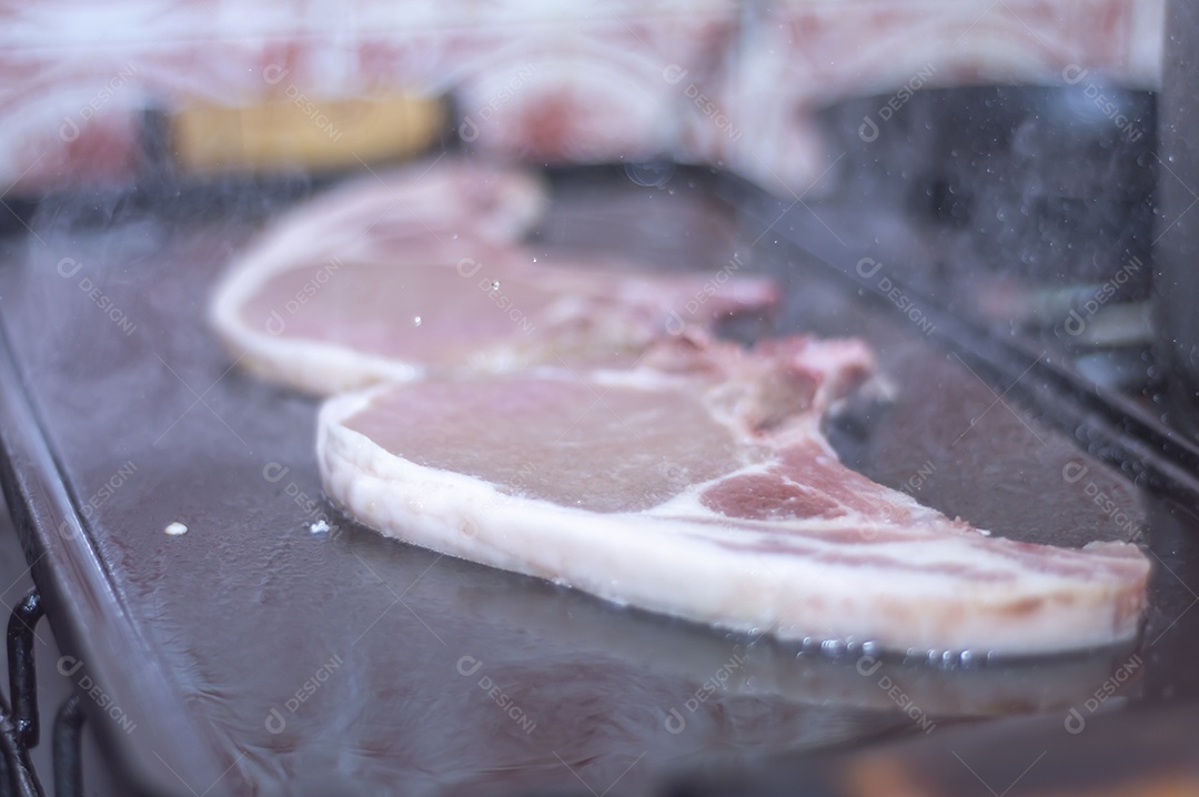 Bife suíno em um churrasco caseiro que fica em cima do fogão, conceito de fazer comida em casa.