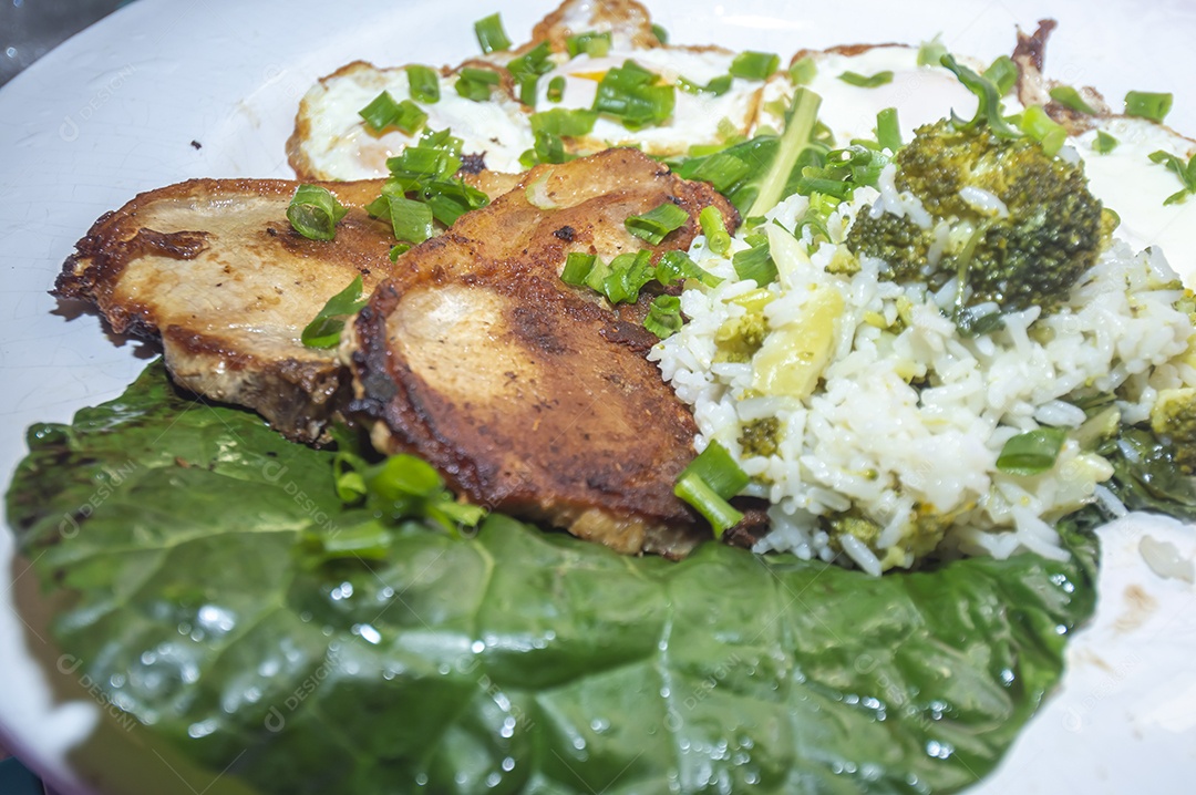 Comida caseira com arroz, ovos, carne de porco, couve-flor e iguarias