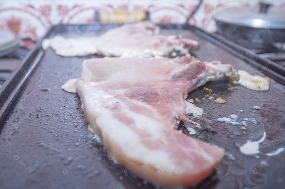 Bife suíno em um churrasco caseiro que fica em cima do fogão