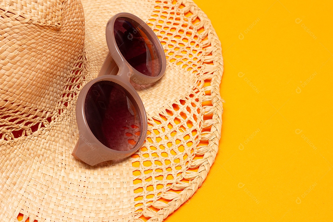 Óculos de sol e um chapéu no fundo amarelo