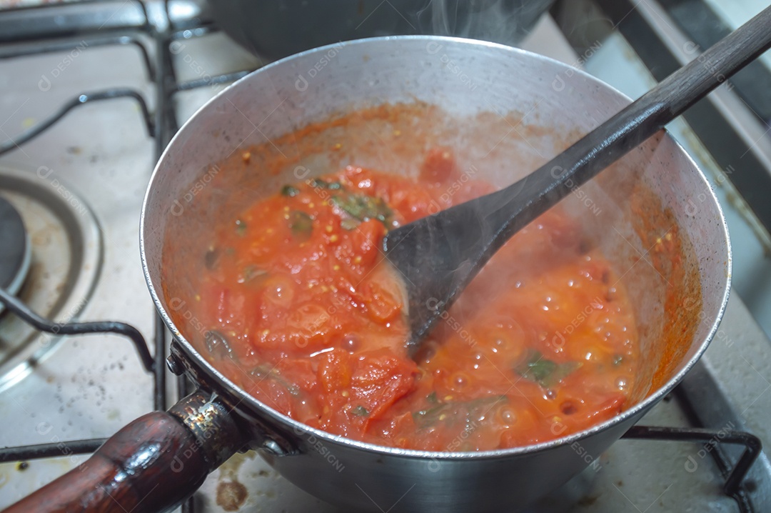 tomate cereja em uma panela sendo cozido com mangericão para fazer molho de tomate natural