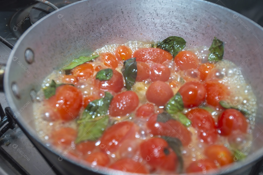 tomate cereja em uma panela sendo cozido com mangericão para fazer molho de tomate natural