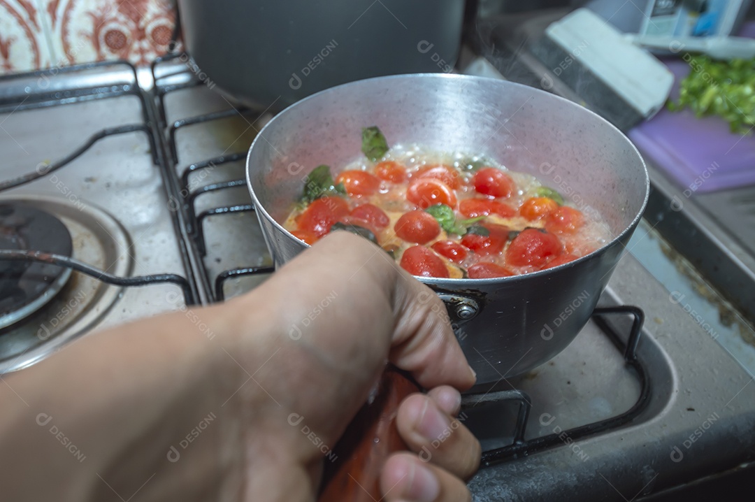 tomate cereja em uma panela sendo cozido com mangericão para fazer molho de tomate natural