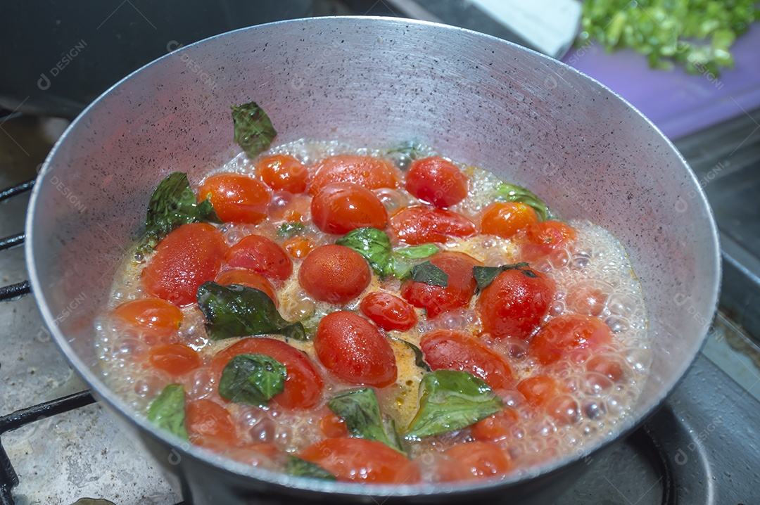 tomate cereja em uma panela sendo cozido com mangericão para fazer molho de tomate natural