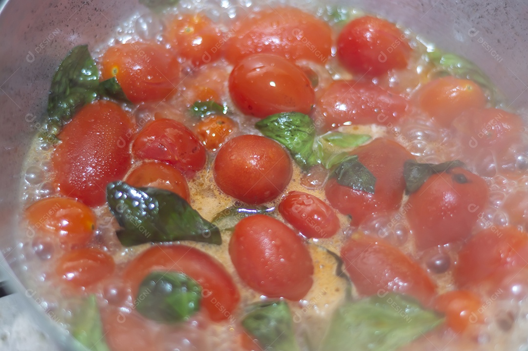 tomate cereja em uma panela sendo cozido com mangericão para fazer molho de tomate natural
