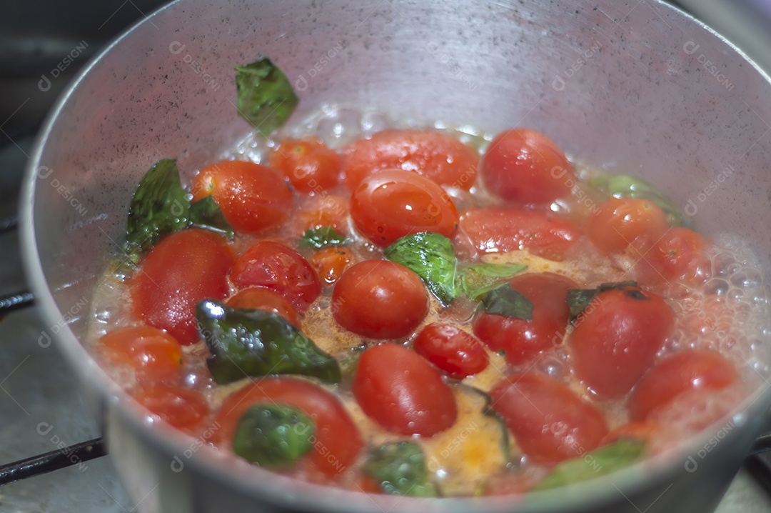 tomate cereja em uma panela sendo cozido com mangericão para fazer molho de tomate natural