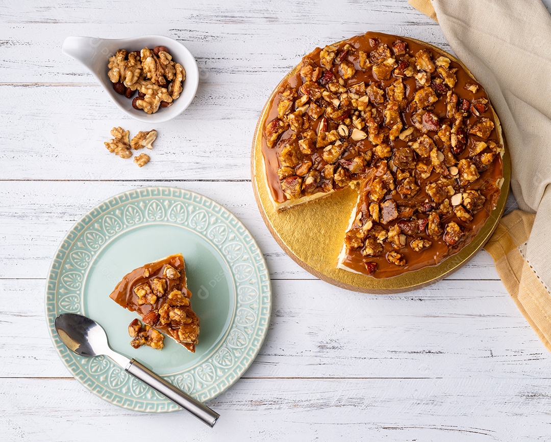 Cheesecake de praliné de amêndoa e noz com uma fatia em um prato.