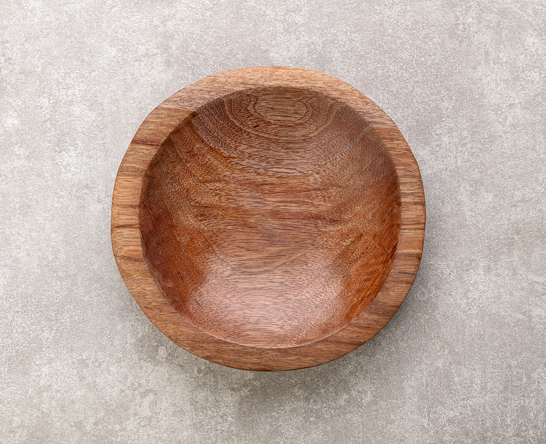 Tigela de madeira artesanal vazia sobre fundo de cimento.