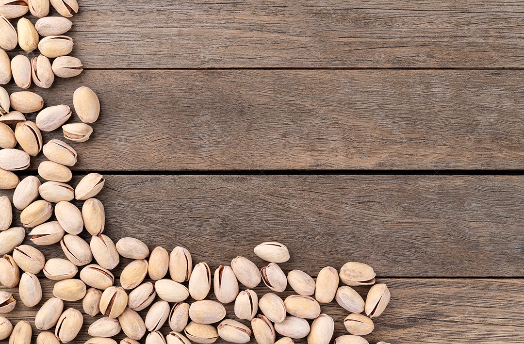 Pistache torrado salgado sobre mesa de madeira com espaço de cópia.