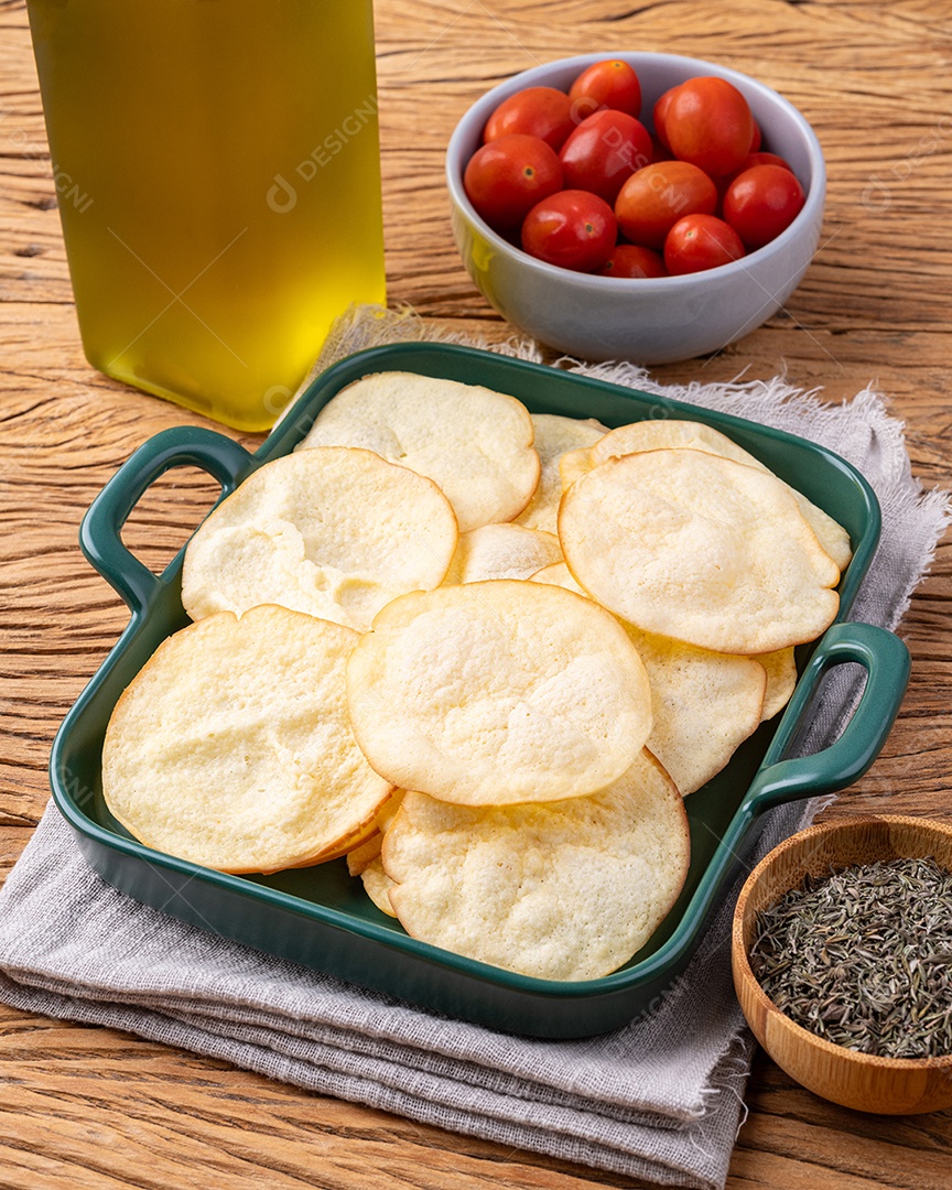Lascas de queijo provolone defumado em uma tigela com tomate cereja e orégano sobre a mesa de madeira.
