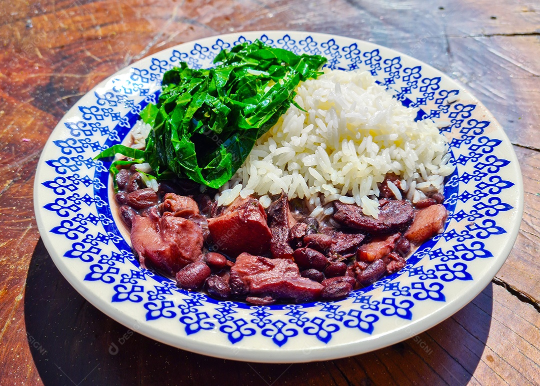 Prato de feijoada com couve sobre fundo de mesa de madeira