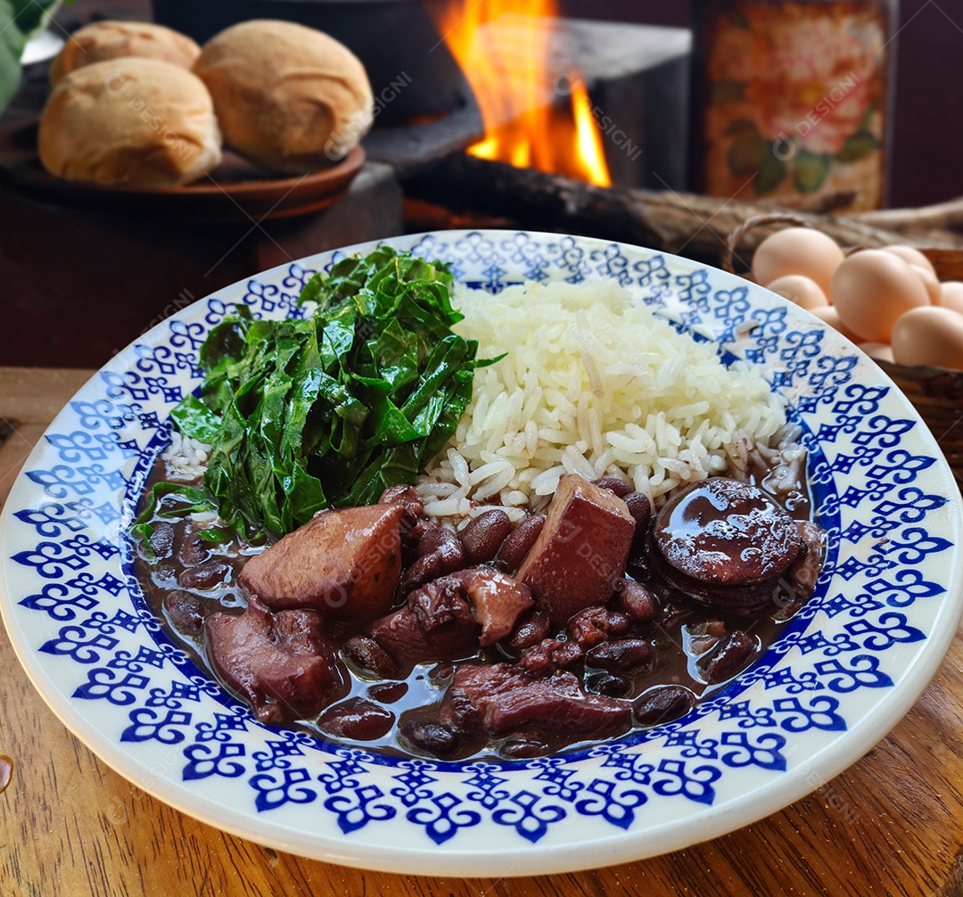 Feijoada deliciosa e acompanhamentos sobre fundo de fogão a lenha