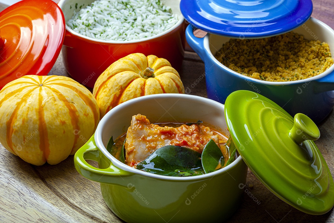 Moqueca tradicional com acompanhamentos sobre mesa de madeira