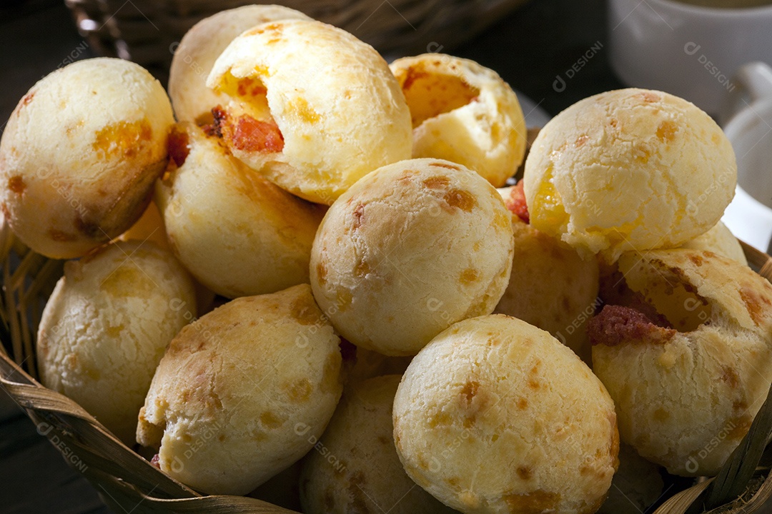 Pães de queijo em cesta sobre mesa de madeira