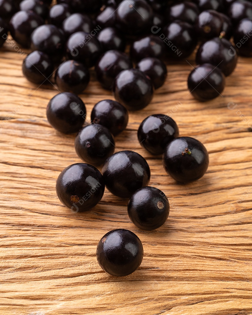 Grupo de jabuticabas sobre mesa de madeira.