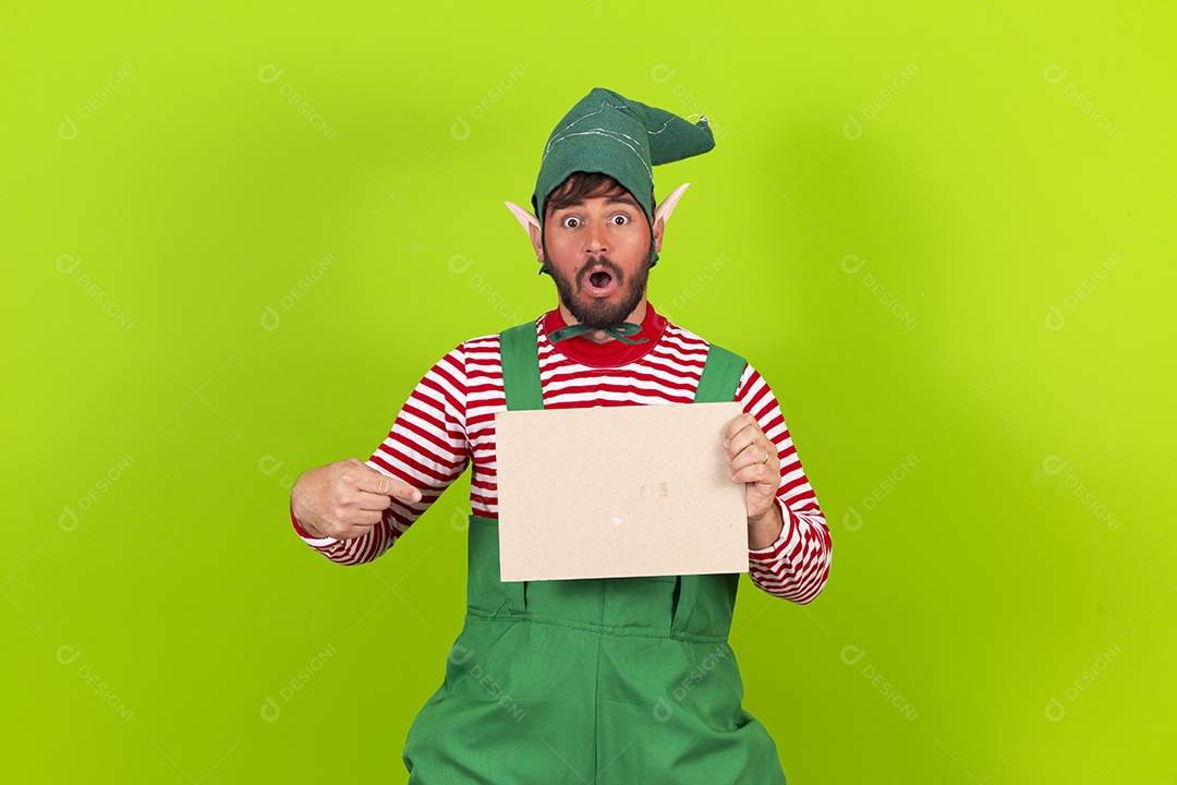 Homem com fantasia de duende segurando placa branca em fundo verde