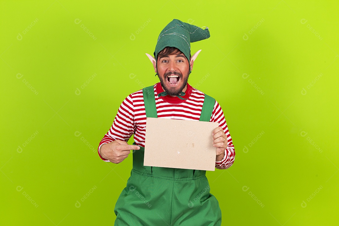Homem com fantasia de duende segurando placa branca em fundo verde