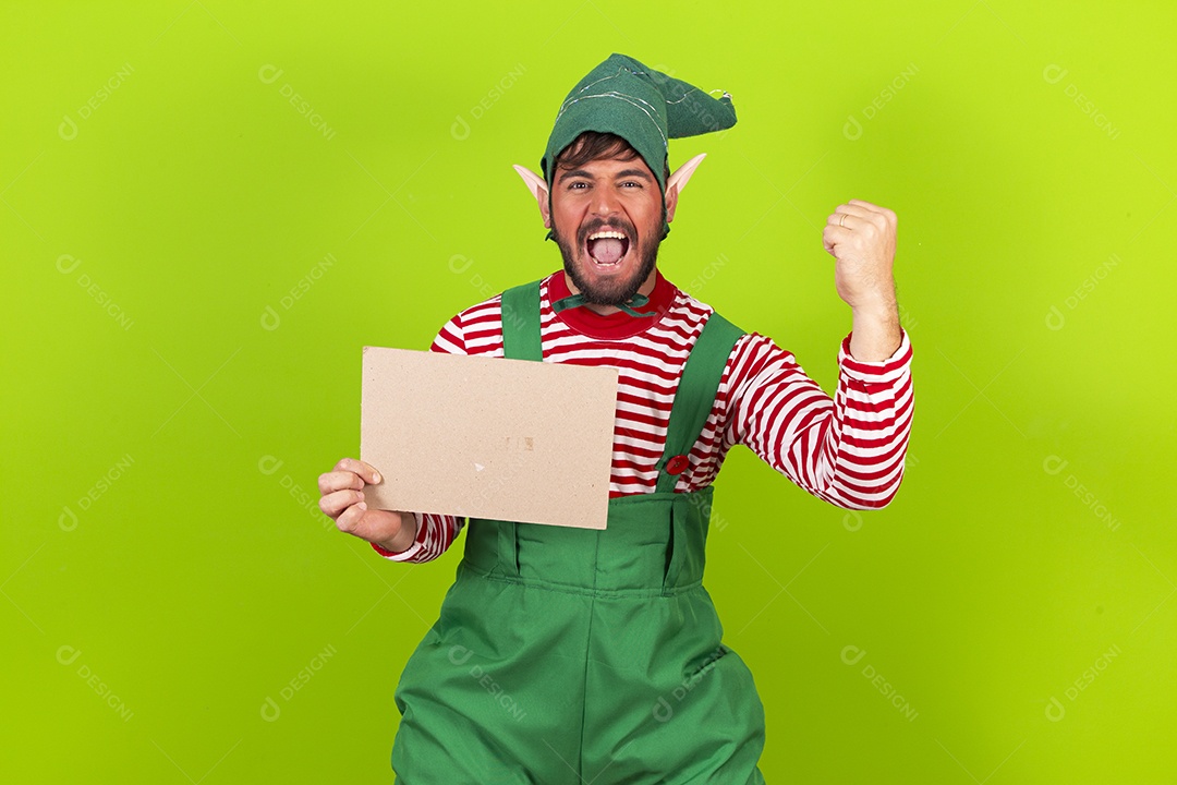 Homem com fantasia de duende segurando placa branca em fundo verde