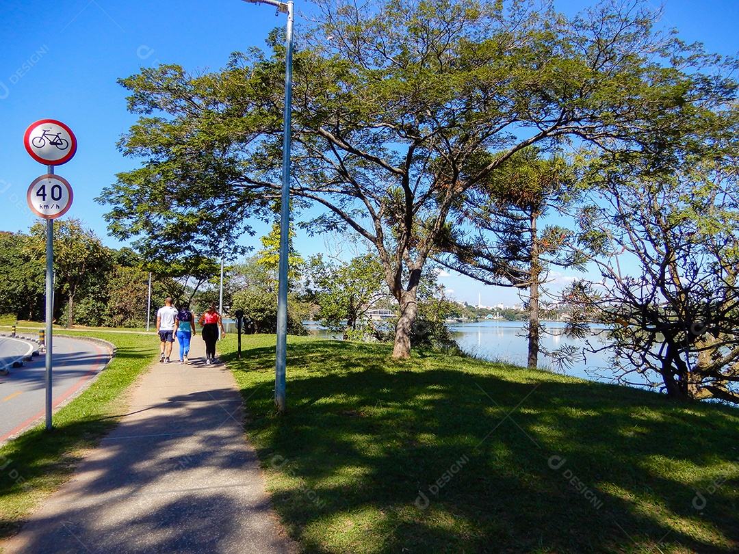 Pessoas fazendo caminhada ao lado da lagoa