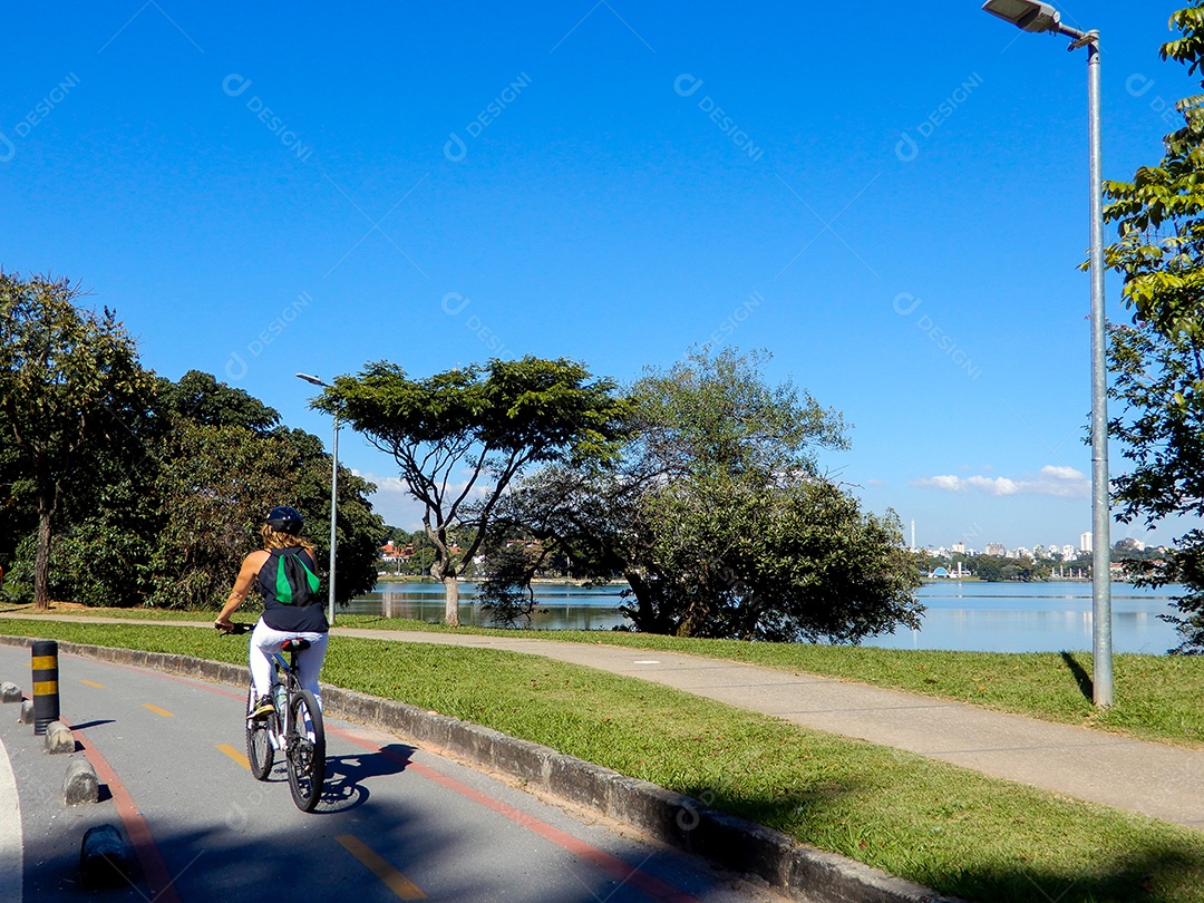 Uma mulher pedalando no bosque da Lagoa da Pampulha
