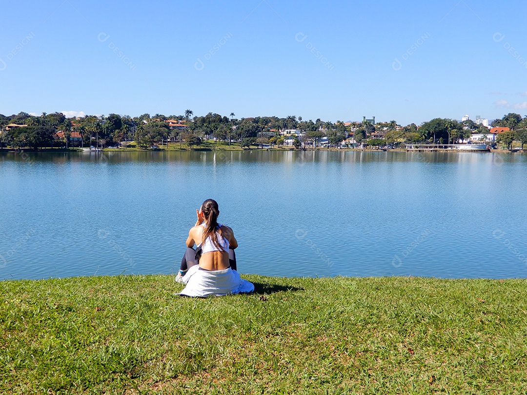 Uma mulher sentada olhando para lagoa