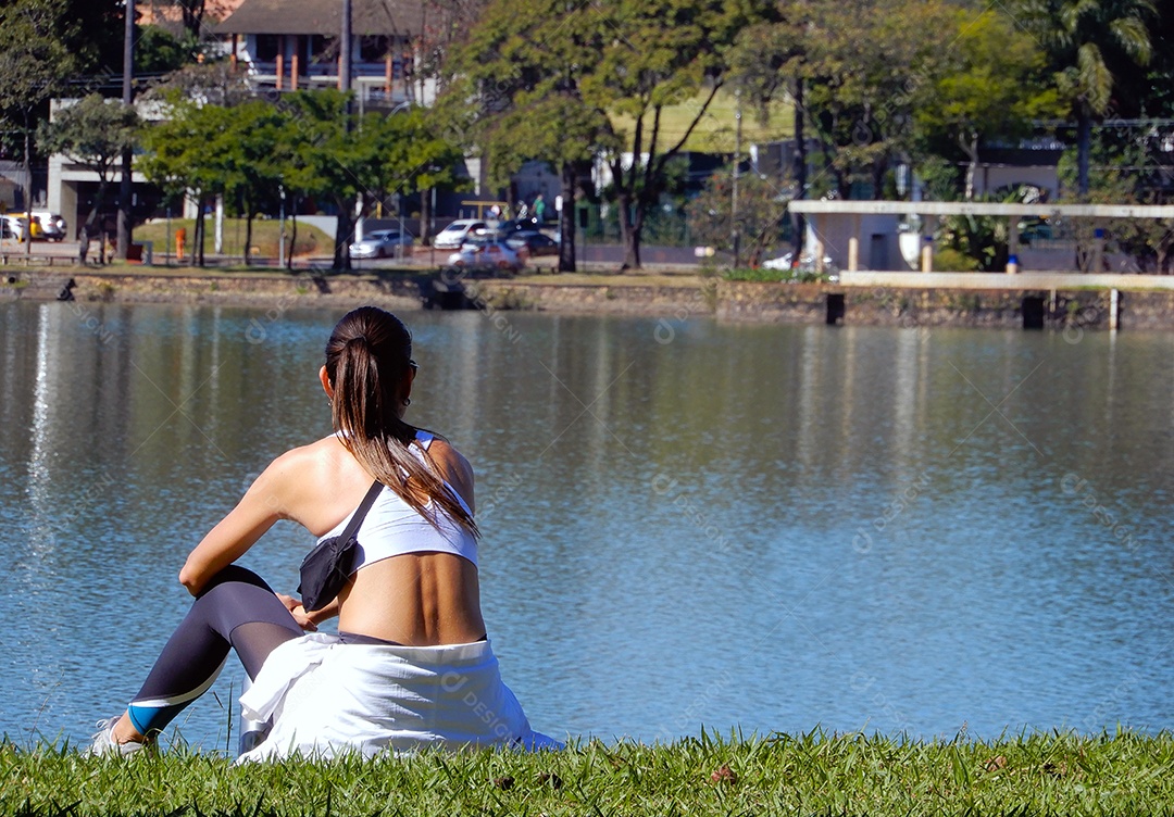 Mulher sentada descansando olhando para a lagoa