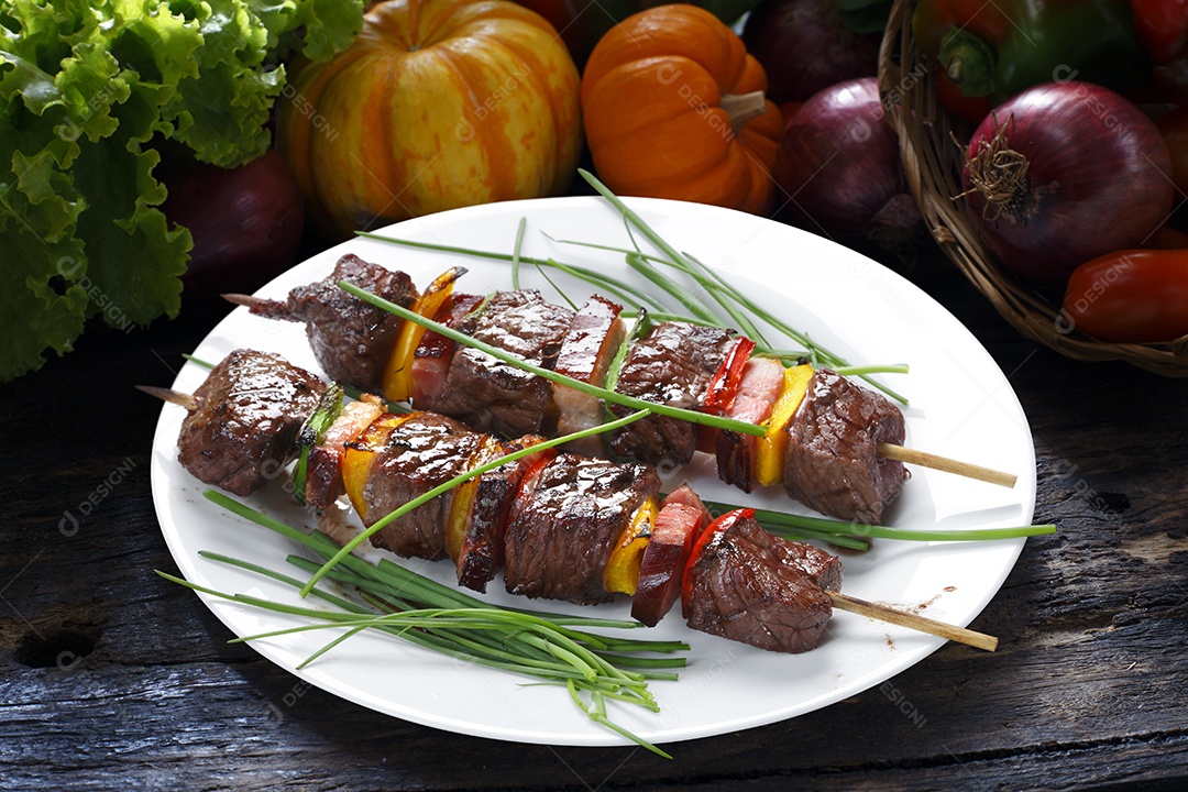 Espeto de carne com legumes sobre um prato branco
