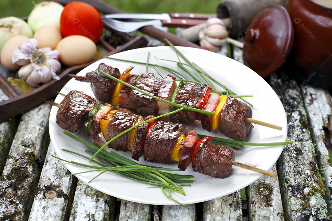 Espetinhos de carne com verduras sobre uma prato branco