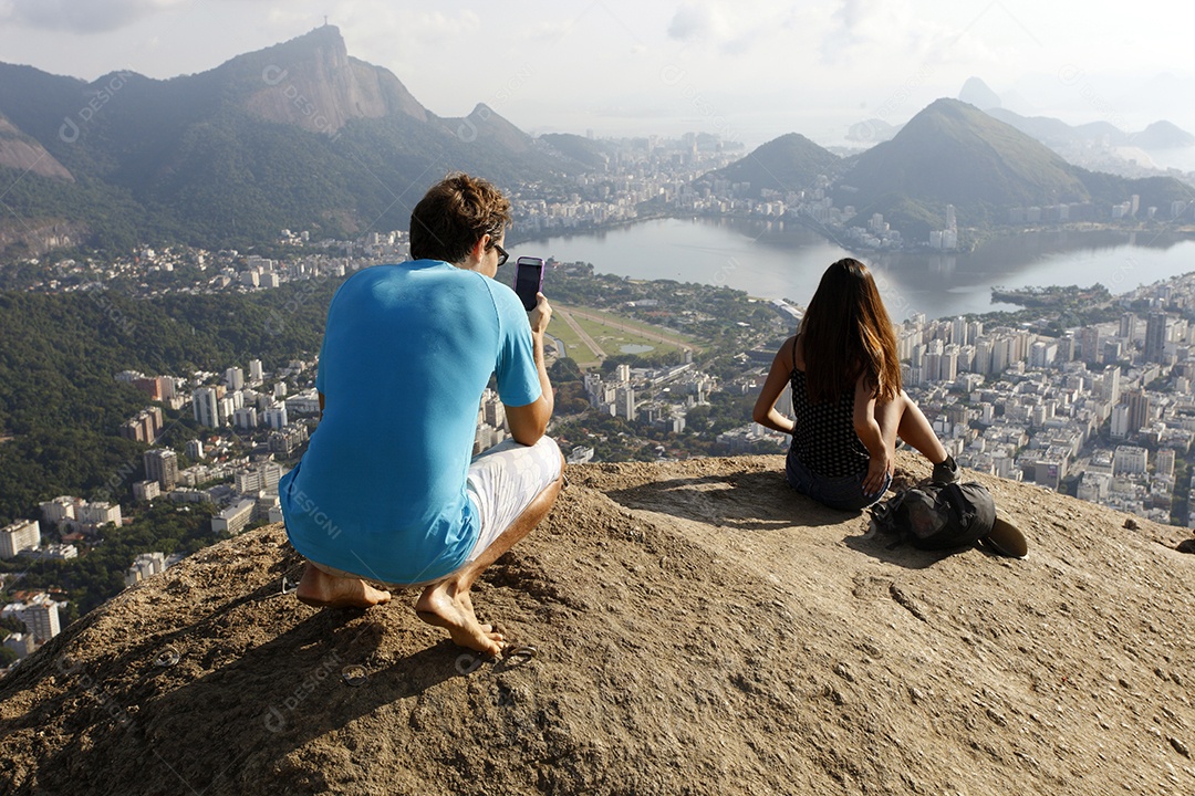 Casal no penhasco com vista para morro de dois irmãos