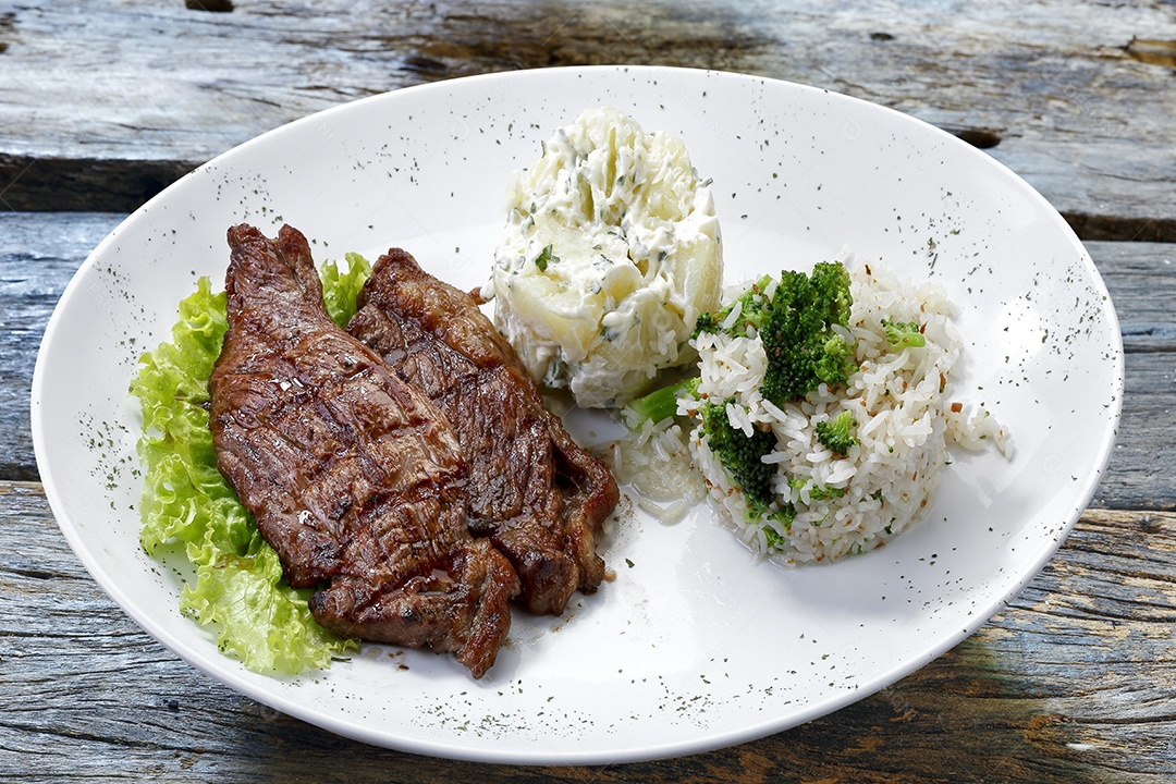 Arroz com carne em um prato sobre mesa de madeira