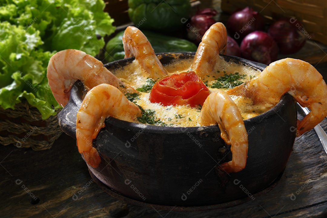 Moqueca de camarão e peixe em tijela sobre mesa de madeira