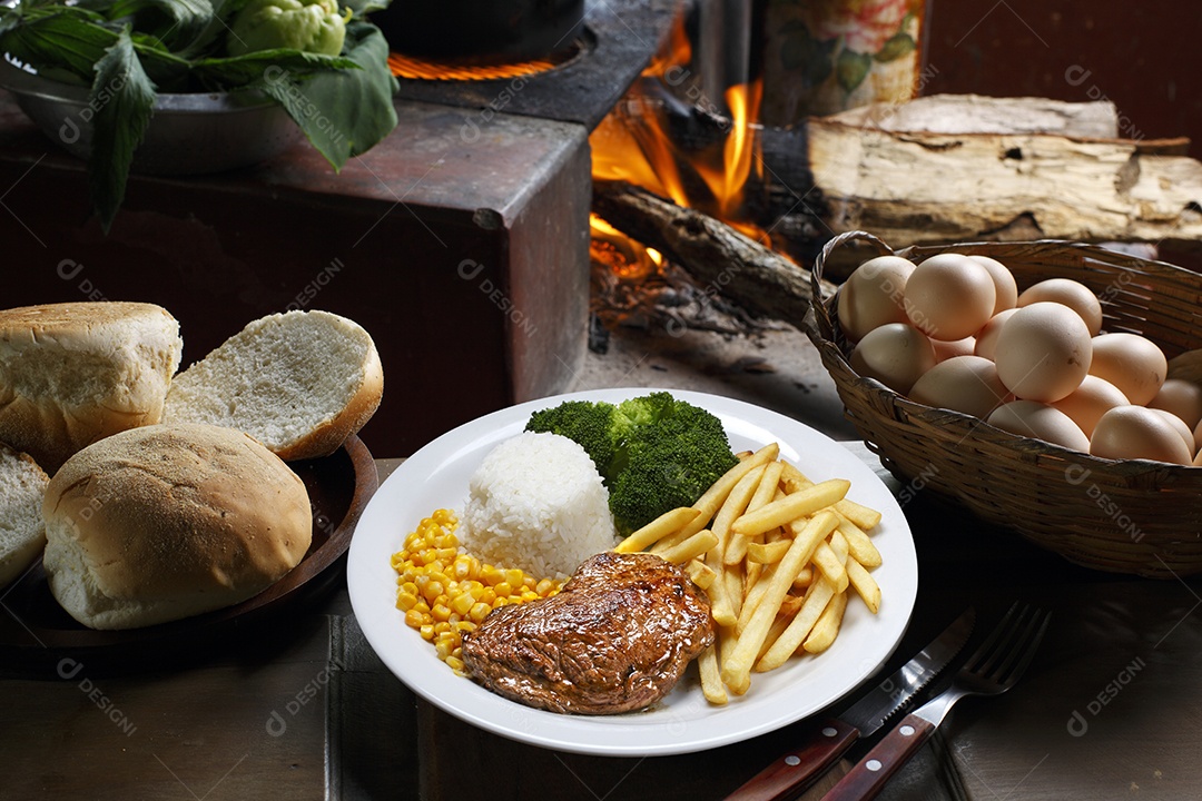 Bife grelhado com batata e arroz em um prato sobre mesa de madeira