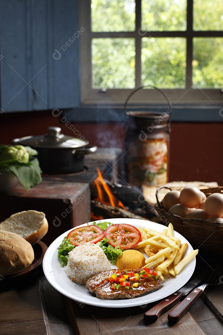 Bife grelhado com batata e arroz em um prato sobre mesa de madeira