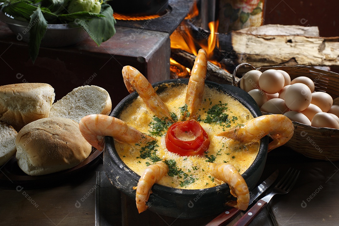 Moqueca de camarão e peixe em tijela sobre mesa de madeira