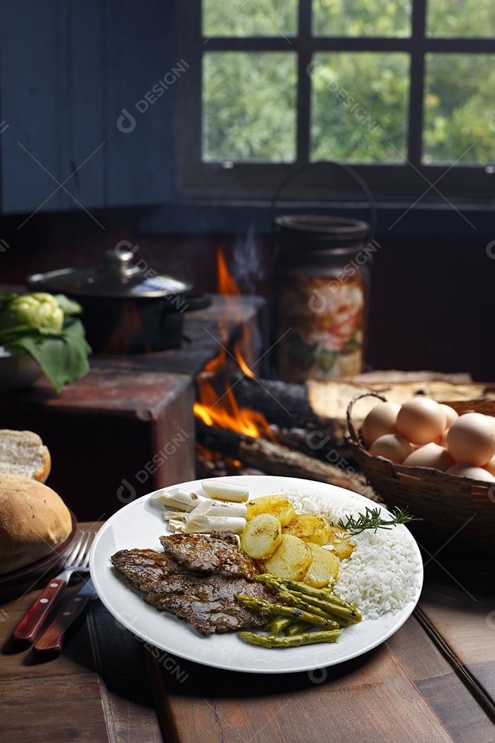 Bife grelhado com batata e arroz em um prato sobre mesa de madeira